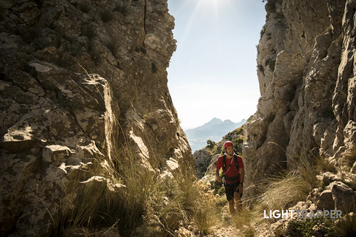 A climber walking in a gorge, surrounded by vegetation