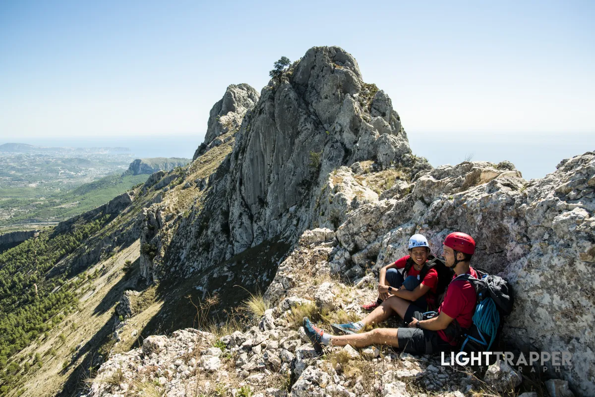 Two climbers chilling on a ridge, resting on a rock that provides them shade