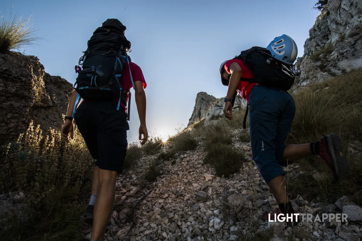 Two climbers walking on steep gravel; shot from behind