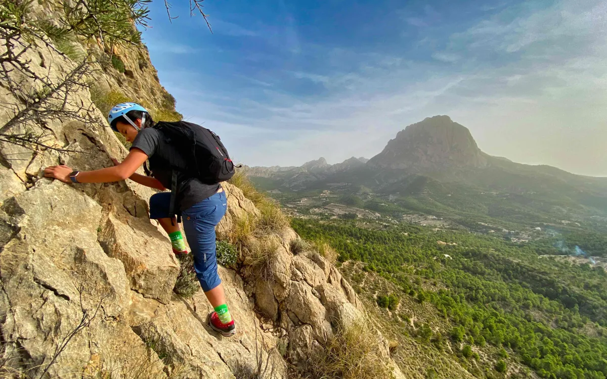 Wendy climbing on a slab; Puig Campana in the background
