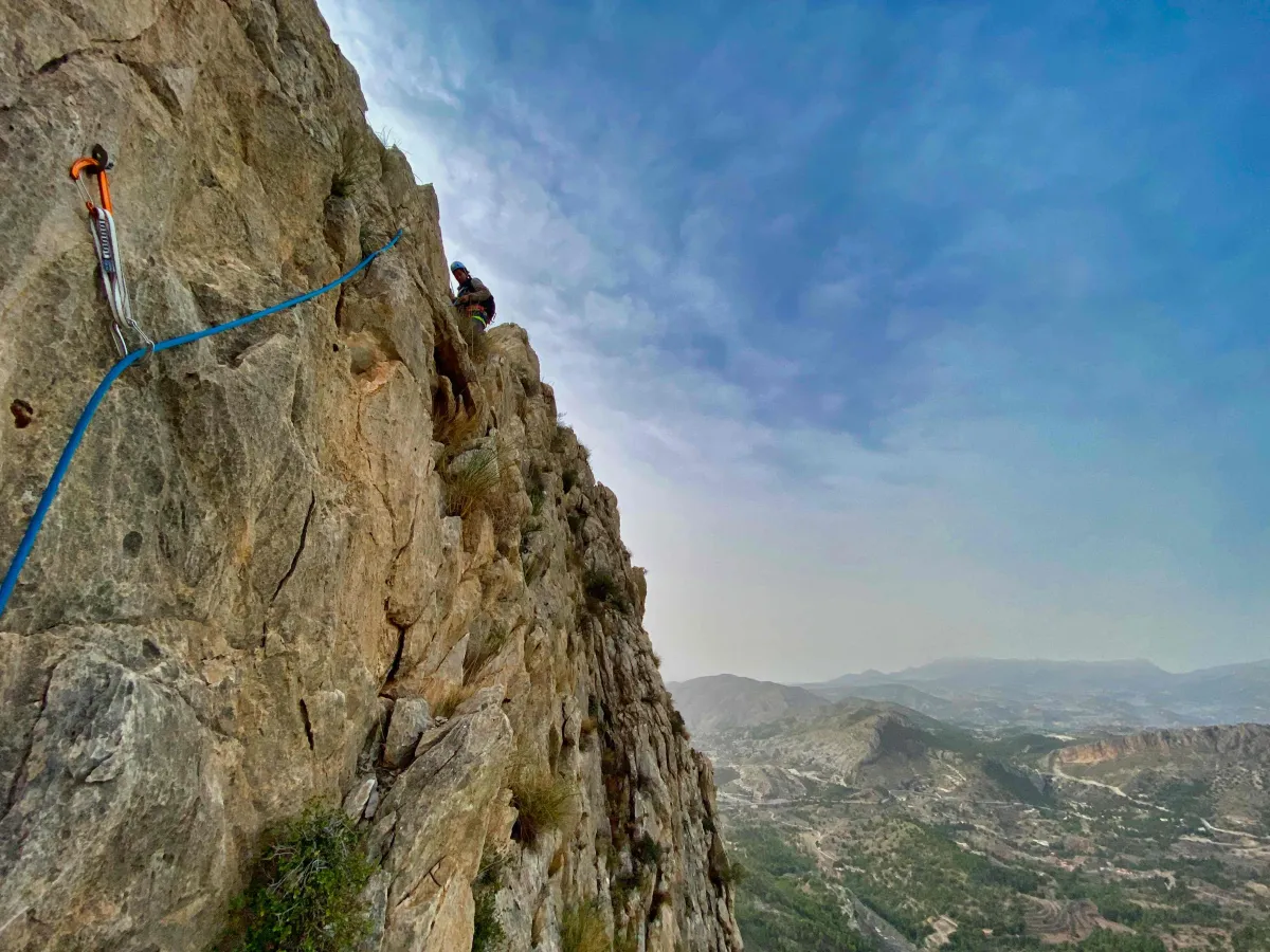 Downclimbing on the crux of the route with a rope and a quickdraw attached to a bolt