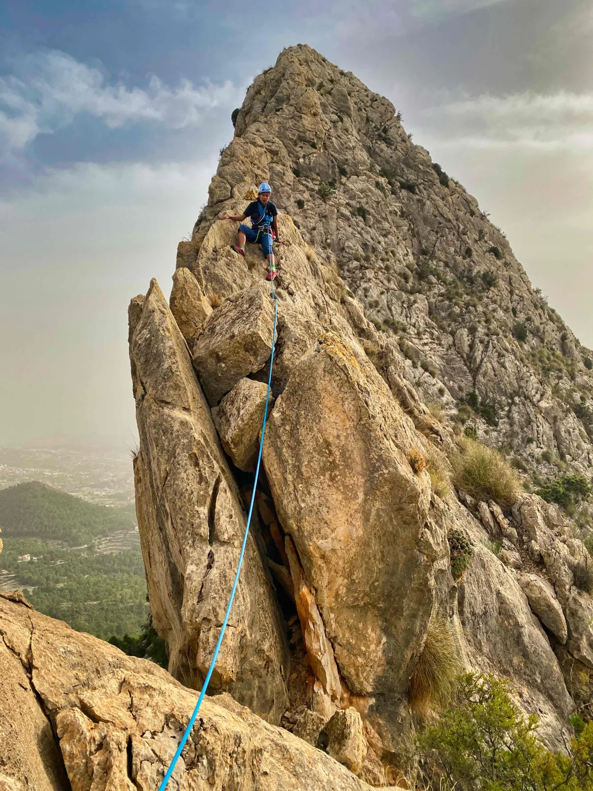 A roped-up climber overlooking a steep section culminating in a tricky downclimb