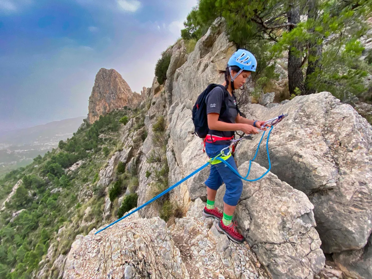 A climber setting herself up for a rappel by putting the rope in her Petzl Reverso