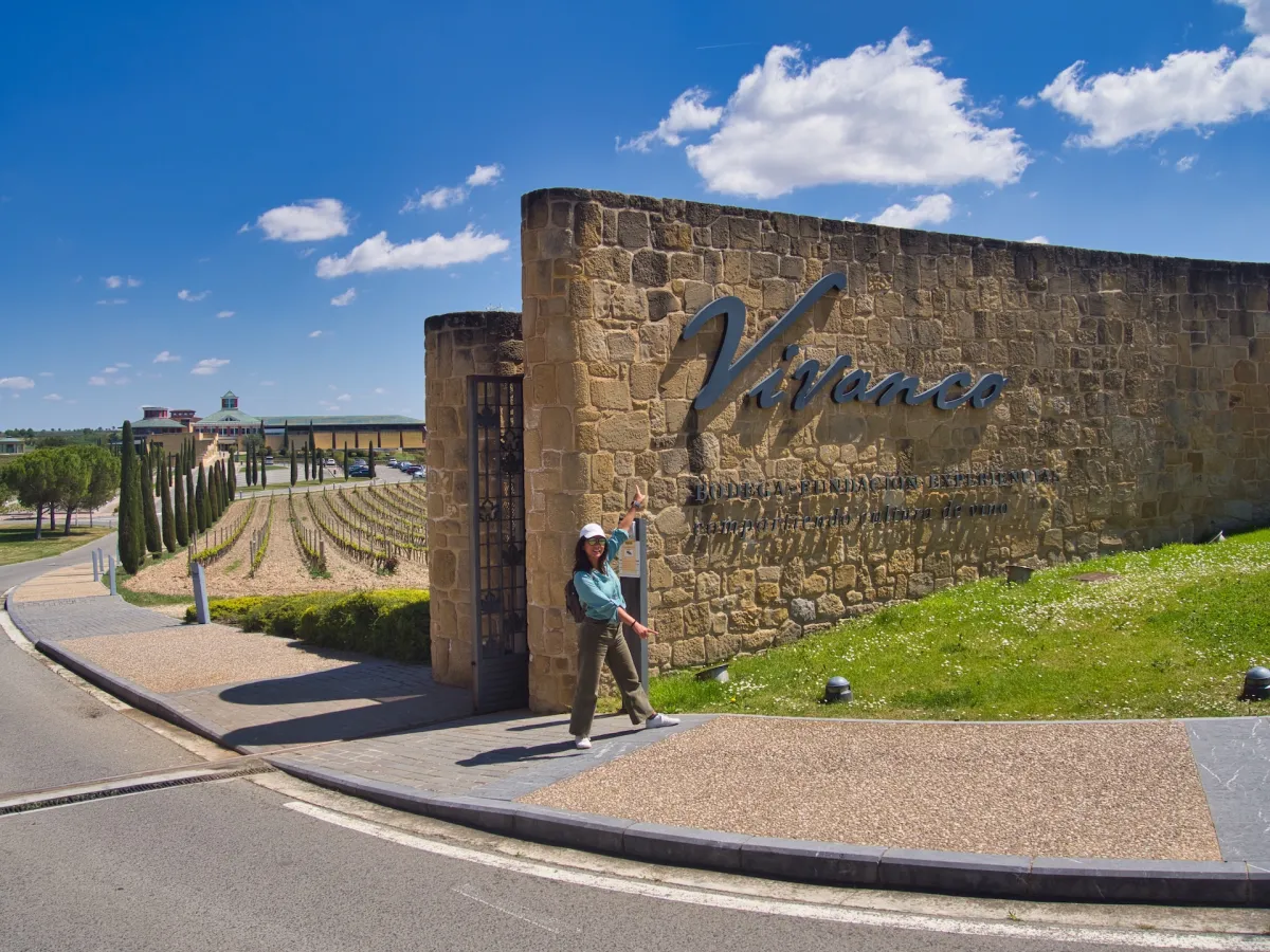 A woman pointing at a stone wall with “Vivanco” written on it