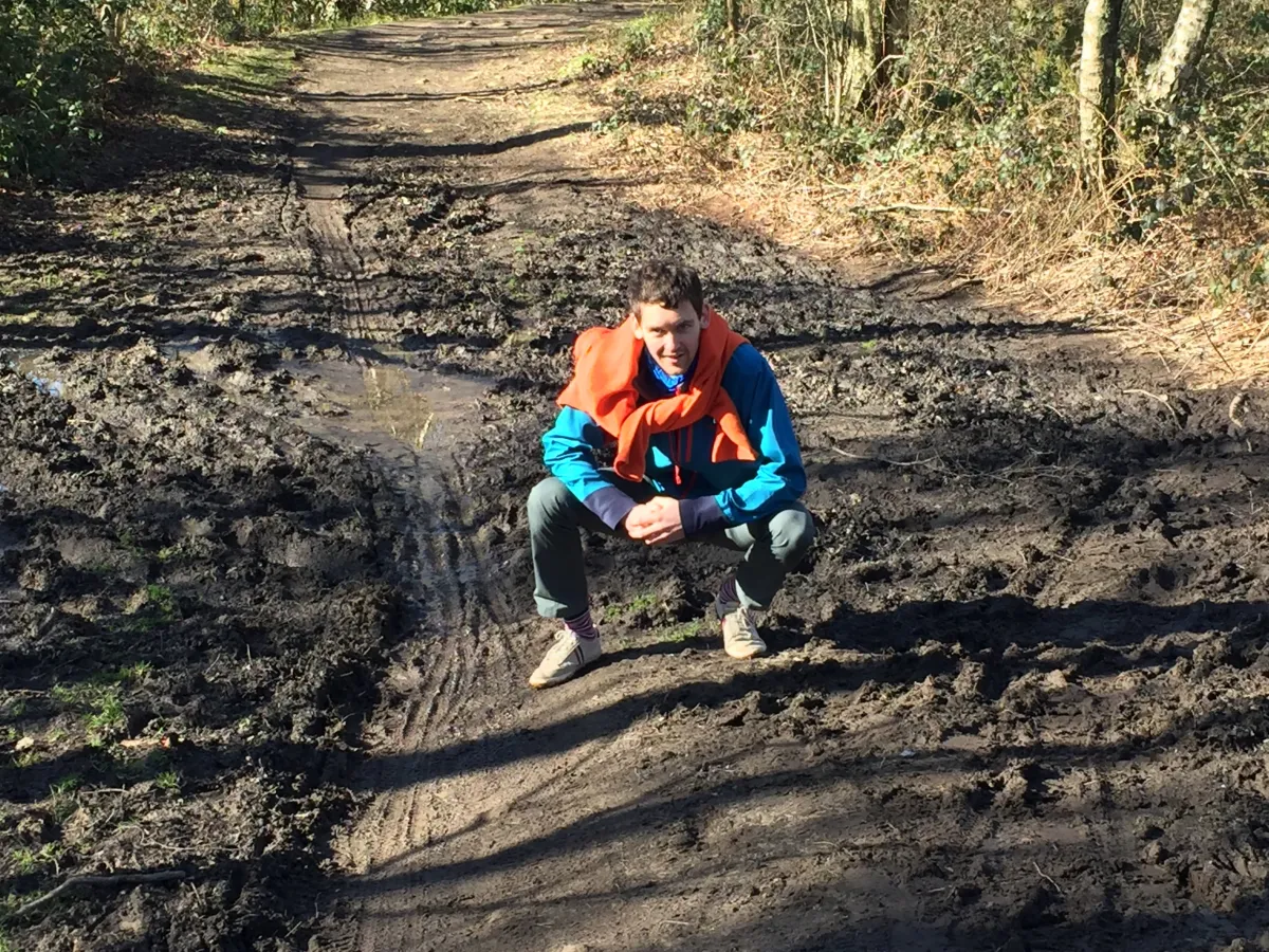 Maciek in a Slavic squat surrounded by mud