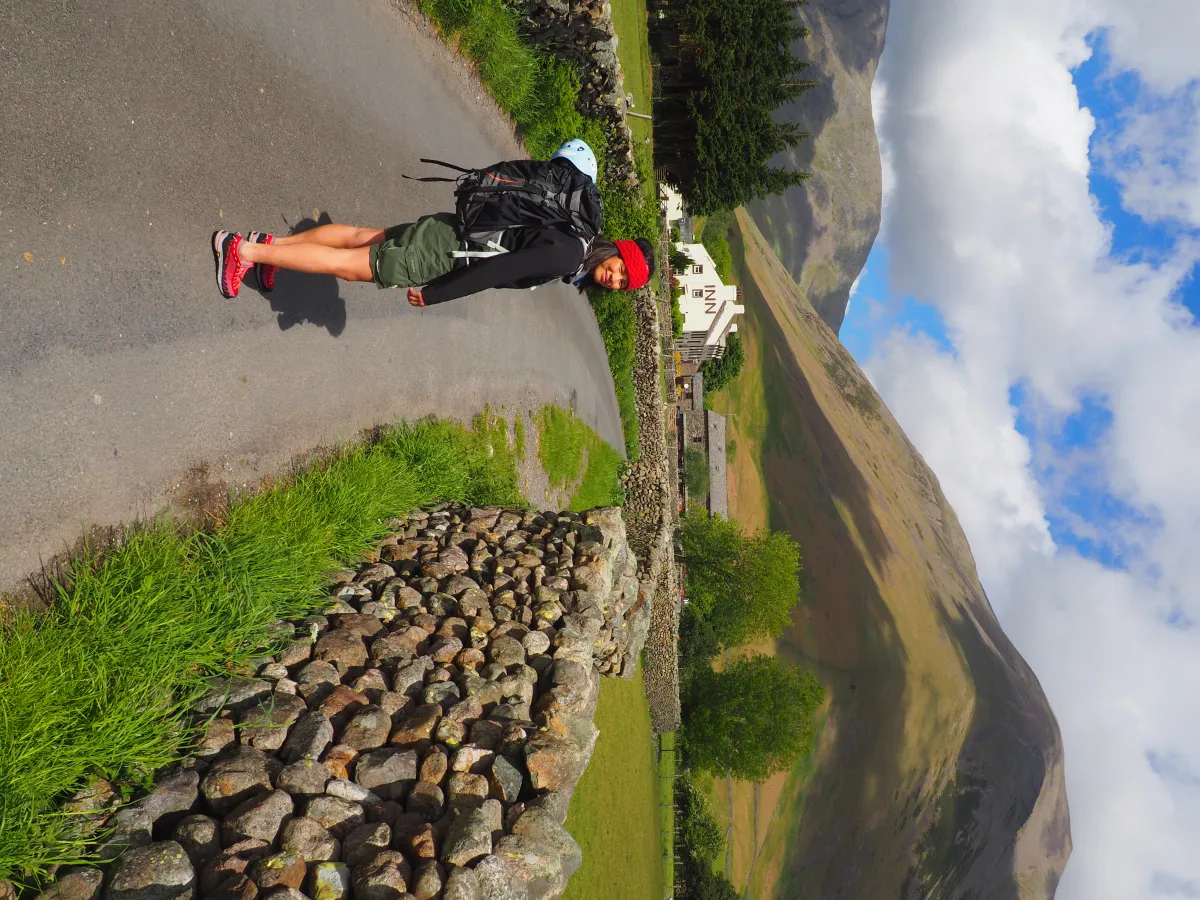 A climber near Wasdale Head car park heading towards Mosdale; Wasdale Head Inn and Kirk Fell in background
