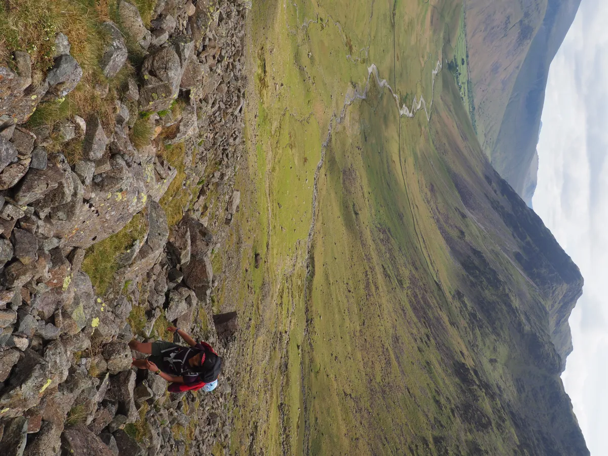 A climber ascending a steep slope surrounded by small boulders